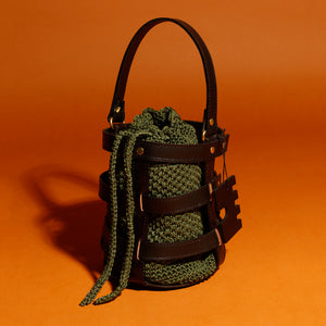 Handcrafted leather and crochet bucket bag inspired by castle doors, featuring black and brown leather with khaki green and light brown crochet bucket. Designed and made in Greece."