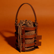 Handcrafted leather and crochet bucket bag inspired by castle doors, featuring black and brown leather with khaki green and light brown crochet bucket. Designed and made in Greece."