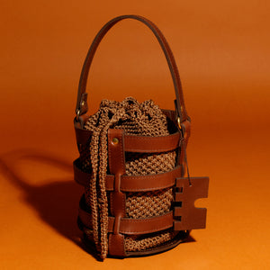 Handcrafted leather and crochet bucket bag inspired by castle doors, featuring black and brown leather with khaki green and light brown crochet bucket. Designed and made in Greece."